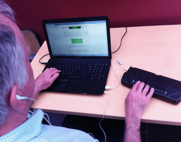 Duine ag úsáid ríomhaire glúine le gléas taispeána Braille inathnuaite ceangailte trí USB